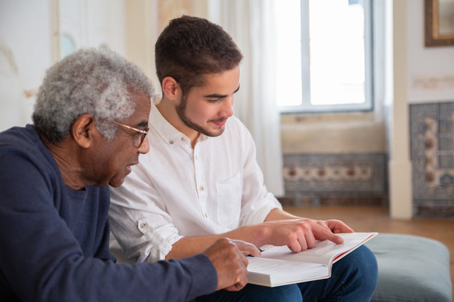 A carer reads a book with an older man